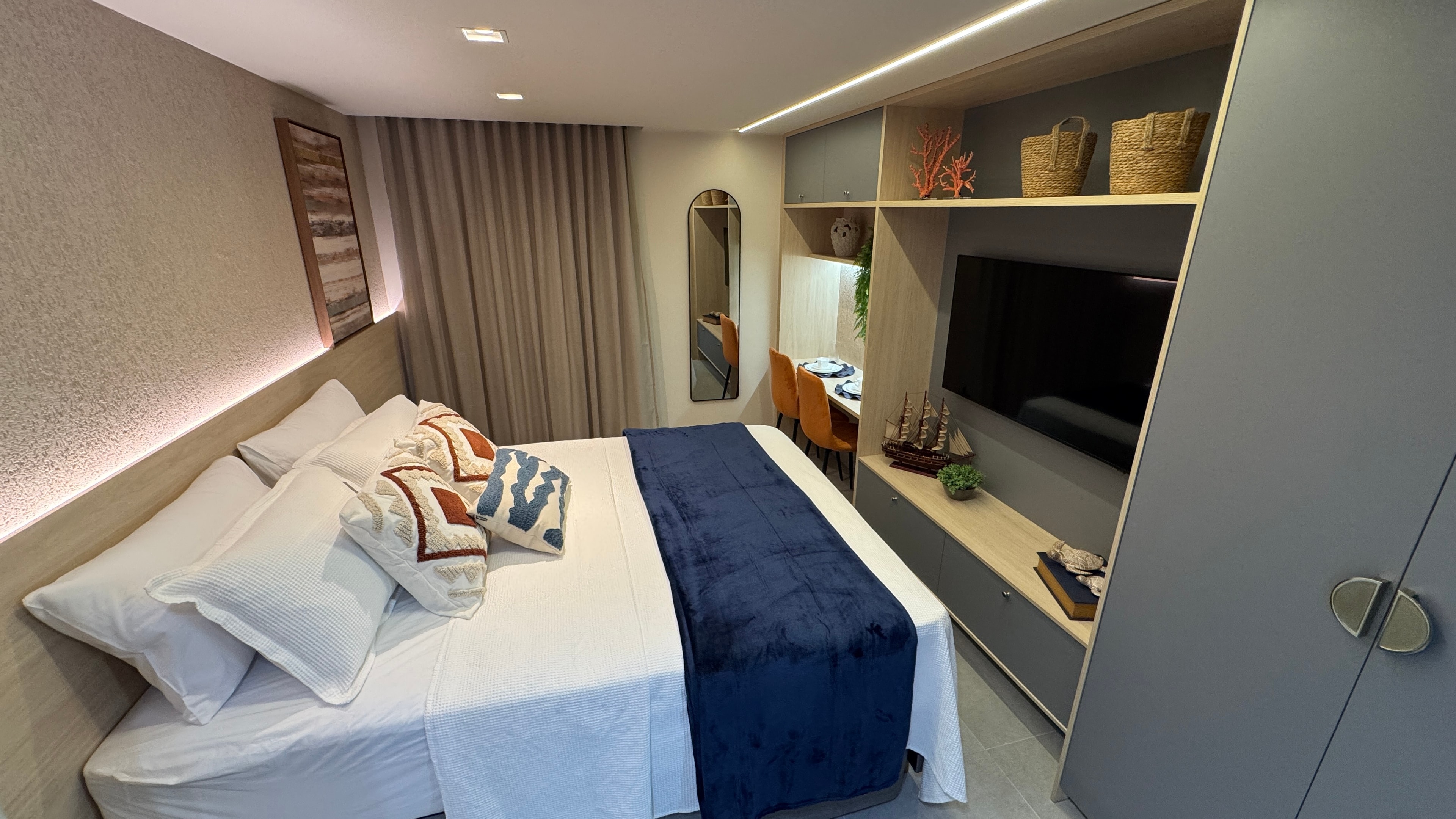 Quarto do flat no Edifício Sonne com marcenaria clara, bancada de trabalho e iluminação indireta